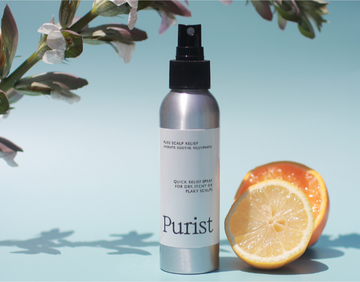 Purist hair care product bottle with lemon and orange slices on a light blue background